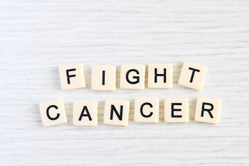 Close up shot of some plastic letter blocks spelling "Fight Cancer" in English on white wooden background.