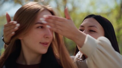 laughter during playful park activity, casual friendship fun involving blindfolds and cheerful greetings, sunshinebright park scene capturing friends enjoying surprise games and hearty laughter