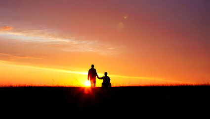 Silhouettes of two people holding hands against a vibrant sunset sky