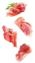 high-resolution photograph of thin, delicate slices of italian prosciutto crudo or cured parma ham floating in mid-air with fresh green arugula leaves.