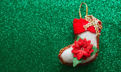 Christmas stocking ornament with poinsettia on green glitter background