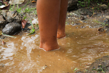 A child's feet standing in a muddy puddle in a wetland area