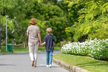Grandmother and grandson teaching pointing sitting in flower garden loving outdoor bonding generational happy family connection. relationship family outdoor summer joyful warm sunlight