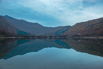 Scenic lake view in Herzegovina with cabins, abstract composition emphasizing water reflections and mountain silhouettes