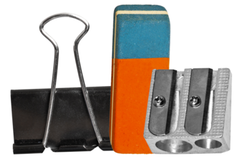 composition of foundational office and school supplies: black binder clip, two-tone rubber eraser, and metal pencil sharpener, isolated on black.