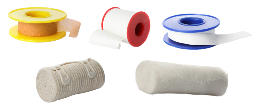 collection of various first aid and medical supplies including rolls of adhesive tape, surgical tape, and elastic compression bandages, isolated on black.