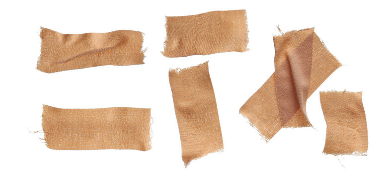 photograph of seven pieces of torn, textured, woven cloth medical plasters and bandages with ripped edges, loosely scattered on a dark transparent background.
