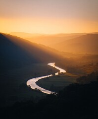 Sunbeam illuminating winding river valley at sunrise nature photography tranquil landscape aerial view serene beauty