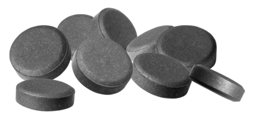 group of rough, dark grey activated charcoal tablets scattered in a pile, emphasizing detox, digestion, natural remedies, and internal cleanse against a high-contrast transparent background.