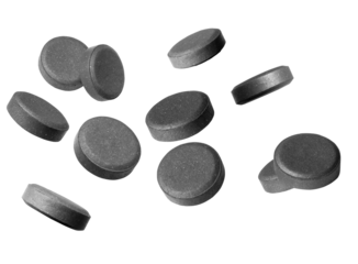 numerous dark grey activated charcoal tablets scattered and isolated against a deep transparent background, highlighting digestive health, internal detoxification, and supplementary medicine.