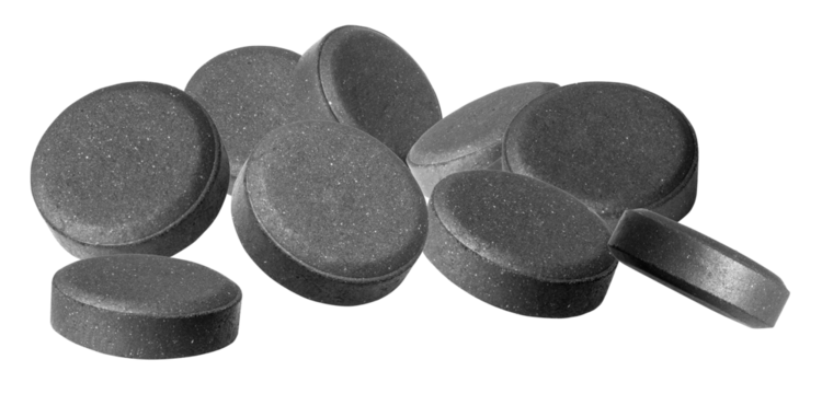 group of rough, dark grey activated charcoal tablets scattered in a pile, emphasizing detox, digestion, natural remedies, and internal cleanse against a high-contrast transparent background.