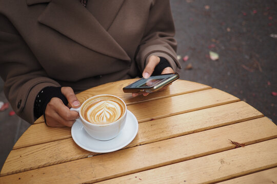 Enjoying coffee while using a smartphone at a cozy cafe - Powered by Adobe
