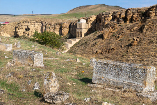 Sarcophagi with incised inscriptions in the foreground with the Diri Baba Mausoleum in the the cliffside beyond