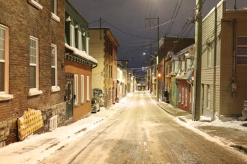 A street in the district of the old Quebec in Canada and in winter. A street with old houses in Quebec city and with a night lighting. Urban snow clearing in the old Quebec city.