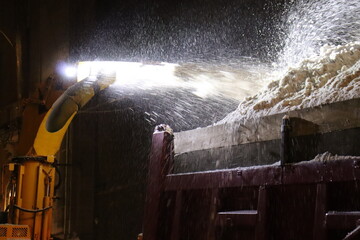 A close-up of a snow blower who put snow in the back of a truck. City snow removel a night in winter. Urban snow clearing in winter.  © Martine