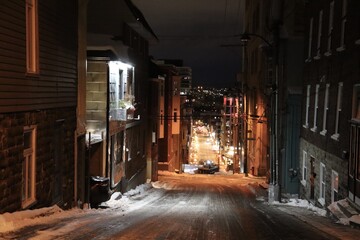 A street in the old Quebec in winter and in evening. Cityscape at night. Winter tourism in Quebec city. A street with snow with a view of downtown. Lighting in evening and a snow plow.