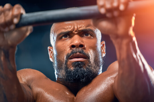 Determined athlete pulls up on bar, pushing limits in intense workout session, glistening skin and powerful physique conveying strength and fitness goals