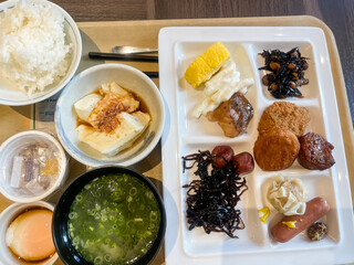 朝食バイキングでプレートに盛ったおかずと豆腐と味噌汁と納豆と温泉卵など。