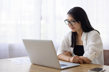 Woman Working on Laptop with Glasses at Desk