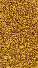 bright yellow raw millet grains forming an organic cereal background with rich natural texture, creating a healthy food concept with warm color and rustic detail