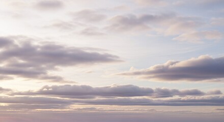 Obraz premium Soft pastel clouds drift across a serene sky, illuminated by the gentle light of dawn or dusk, creating a peaceful and tranquil atmosphere