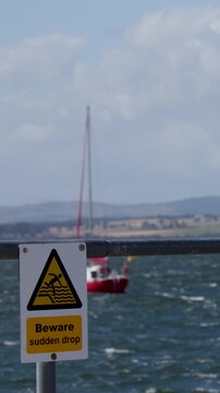 Windy Cromarty Pier With Sailboats and Warning Sign