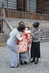 Fototapeta premium A woman is holding a baby in a red and white outfit. The woman is wearing a gray outfit