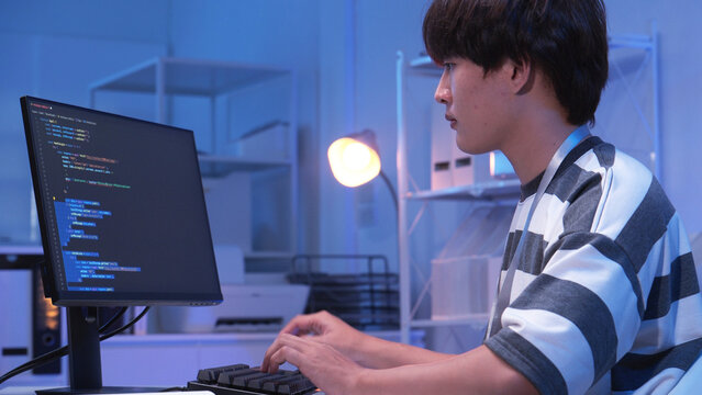 One young male Asian IT freelancer programmer and tech engineer working with computer keyboard, typing software codes for application development and website network system information data in room.