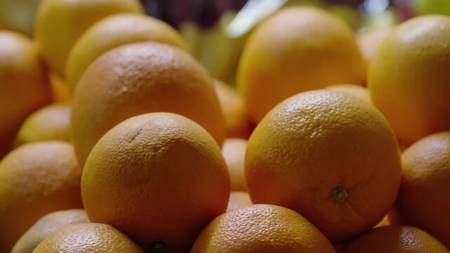Close-up view of a vibrant pile of ripe oranges with textured dimpled peels, showcasing fresh citrus fruit arranged in a market-style display under soft natural light.