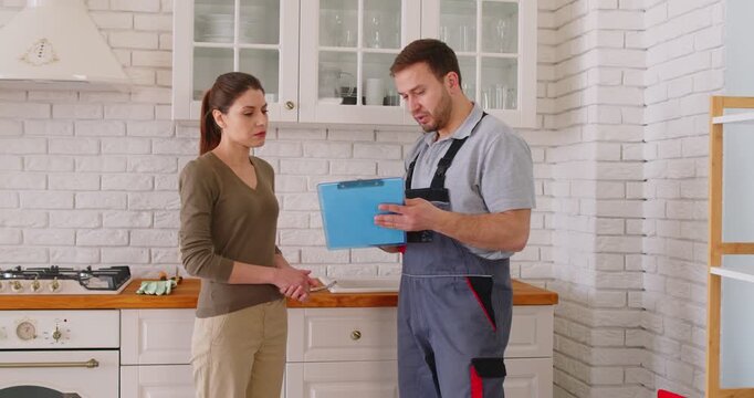 Plumber professional worker giving, signing documents with client after he repairs pipes, fittings, water supply, sanitation, heating systems plumbing, sewage, heat pumps and installations, cleaning