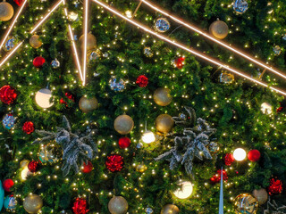 Background, a glowing Christmas tree decorated with red and gold baubles ornaments perfectly...
