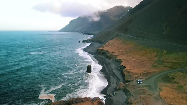 Scenic coastal view of Stapi in Stapav&iacute;k, a freestanding volcanic rock formation on a black sand beach in Eastern Iceland.