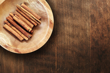 Wooden plate with cinnamon sticks on a wooden table