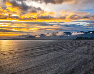 Fototapeta premium Empty asphalt race track road and mountain landscape under dramatic sunset sky