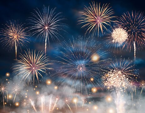 A stunning display of golden and blue fireworks lighting up the cloudy night sky for a festive celebration