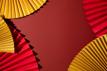 Close-up of top view of red and gold fans, forming a striking textured pattern. Perfect for designers needing a bold, abstract New Year backdrop. Copy space