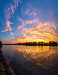 Fototapeta premium Stunning river at sunset, with fiery clouds and calm waters reflecting