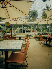 Relaxing at a trendy outdoor cafe, perfect for a summer brunch or afternoon tea in a serene environment with vibrant greenery and wicker chairs