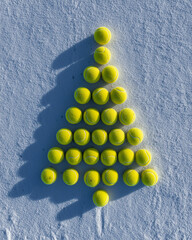 Padel and tennis balls arranged on fresh white crispy snow in the shape of a Christmas tree