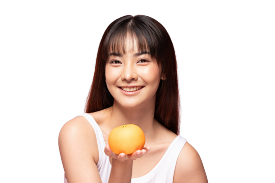Asian Smiling young woman with straight bangs holding orange fruit in open palm, studio portrait with bright skin and casual tank top conveying fresh cheerful mood