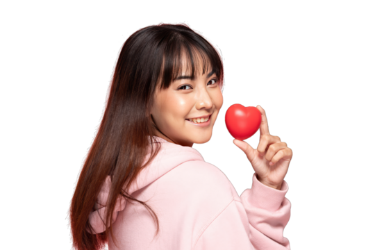 Asian Smiling woman holding red heart stress ball, casual pink hoodie, studio portrait expressing warmth and affection