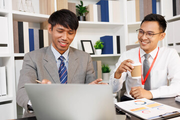 Two men are sitting at a desk, one of them is holding a piece of paper. They are having a conversation, and it seems like they are discussing something important. The atmosphere is tense
