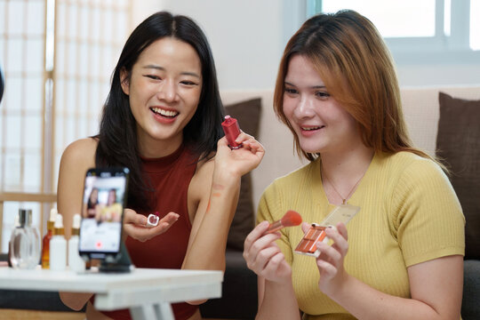 Social Media. Friends sharing beauty tips while filming a makeup tutorial indoors.