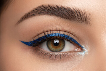 Fototapeta premium Beautiful eye with bold blue winged eyeliner and glitter makeup