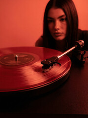 Obraz premium Red Vinyl Spinning on Turntable with Retro Mood Lighting and Soft Background Blur