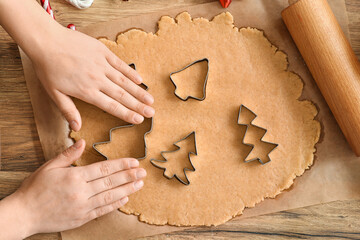 Woman with cutters making Christmas gingerbread cookies on table in kitchen, top view