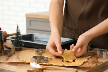 Woman putting gingerbread Christmas cookies on baking tray in kitchen, closeup