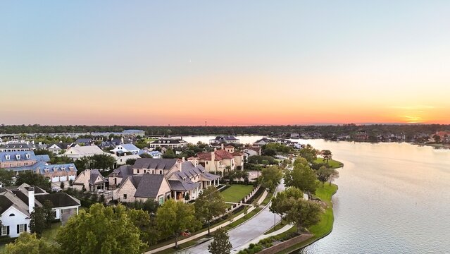 Aerial view of large mansion houses with swimming pool, in affluent neighborhood by Woodlands lake, Houston, Texas, expensive suburban homes surrounding by lush green trees at sunset, USA