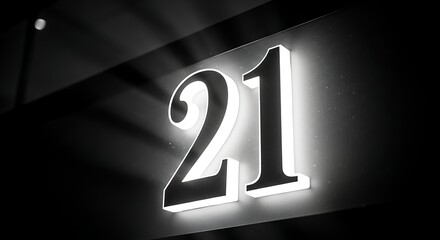 Illuminated number twenty one sign on a dark wall in black and white