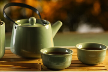 Tray with teapot and cups of hot tea on green grunge table outdoors